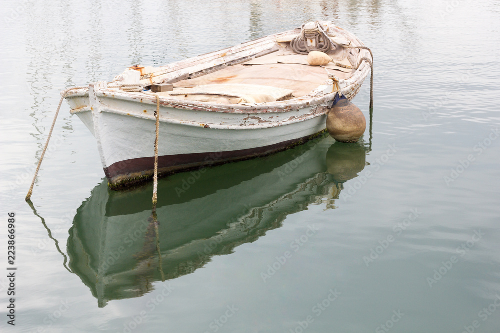 Old white weathered wooden rowing boat or dinghy moored in a harbour in  Greece. Stock Photo