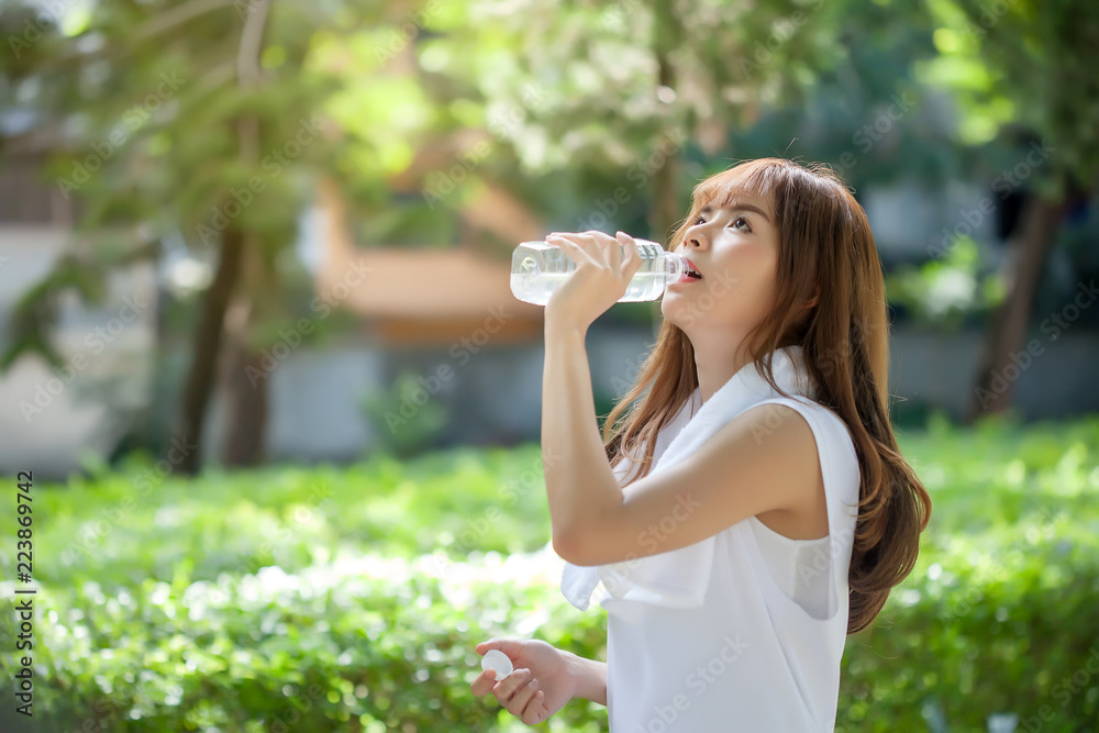 Asian young woman drinking water after workout exercising. Asian young woman drinking water after workout exercising.
