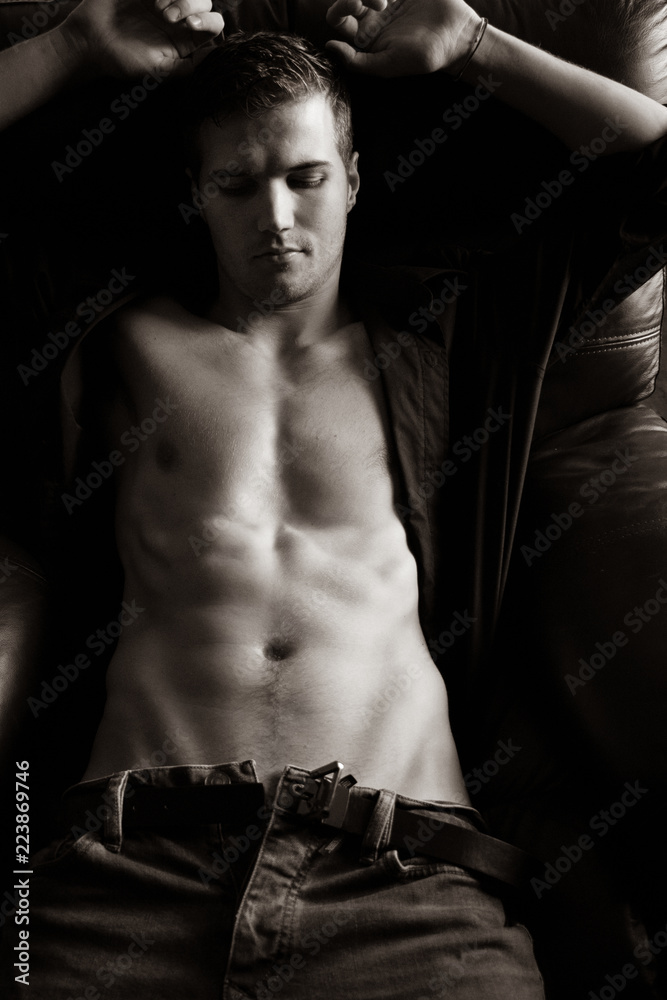 Good looking man with pecs and six pack abs sitting on armchair