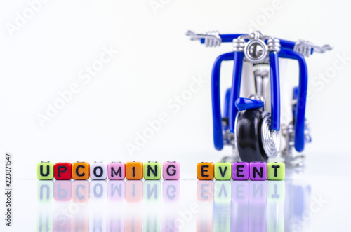 UPCOMING EVENT word block and miniature motorcycle concept on white reflection table
