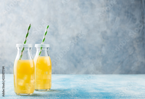 Fresh pineapple juice and ripe pineapple on grey background