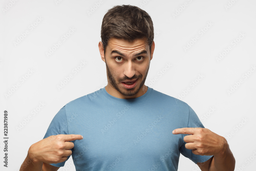 Young man in blue t-shirt pointing to himself with question if he did something wrong. You talking to me? Young man in blue t-shirt pointing to himself with question if he did something wrong. You talking to me?