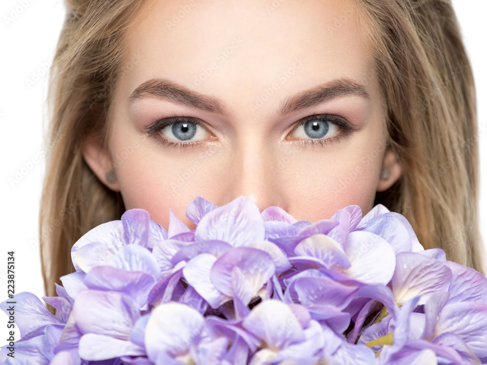 Woman hiding half of face behinde flowers Woman hiding half of face behinde flowers