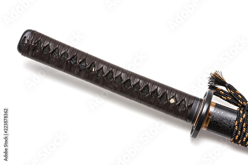 Tsuka: Handle of Japanese sword  isolated in white background. Black rayskin and brown leather cord with steel fitting. photo