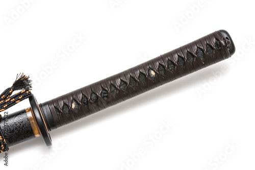 Tsuka: Handle of Japanese sword  isolated in white background. Black rayskin and brown leather cord with steel fitting. photo