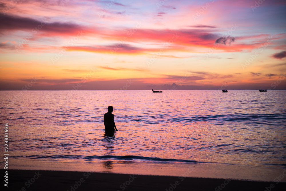 Young man enjoying a purple sky sunset in a calm sea in Caribe, Trinidad and Tobago, Caribe
