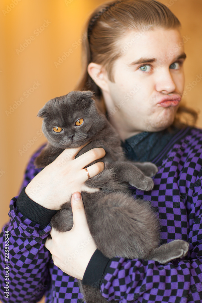 Obraz premium Young man holding a gray Scottish fold cat.