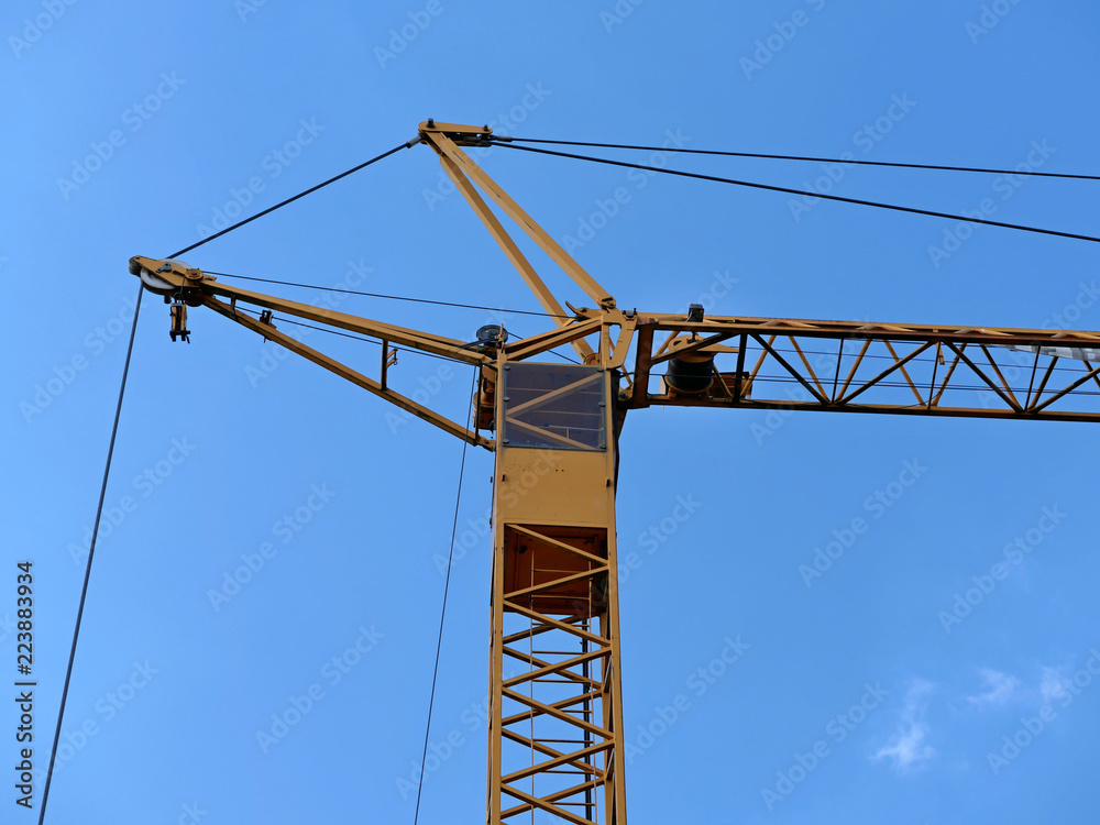 yellow construction crane in front of a blue sky yellow construction crane in front of a blue sky
