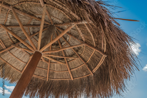 Fényképezés View overhead of a round palm palapa against a tropical blue sky.