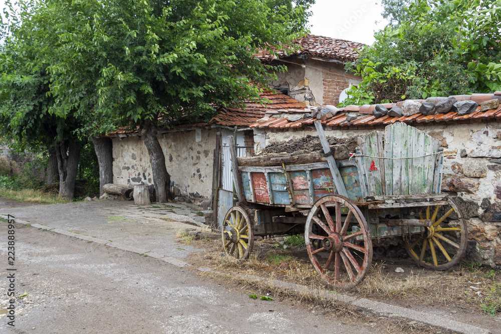 A loaded with compost colored old cart in front of a house at the Rhodope Mountains village of Bukovo, Bulgaria on a rainy July day