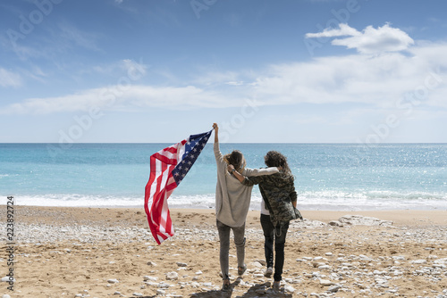 Two girls holding United states of America flag in beach