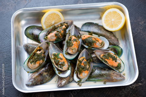 Oven-tray with green mussels stewed in white wine with addition of parsley and lemon, horizontal shot