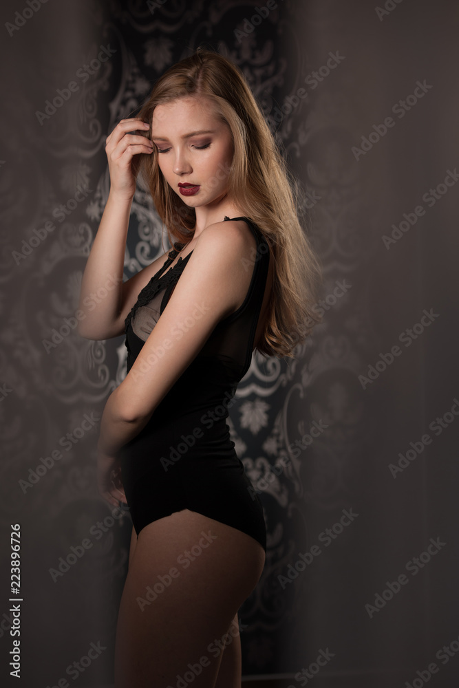 Boudoir photography of a beautiful young lady in black body over dark stylish background