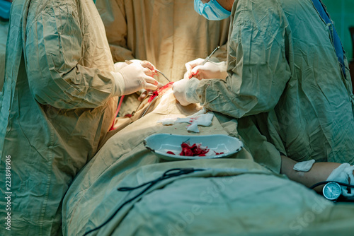 surgeons perform an operation on the patient's face and stop the blood with medical gauze. Pieces of bloodied gauze lay on the plate on the patient