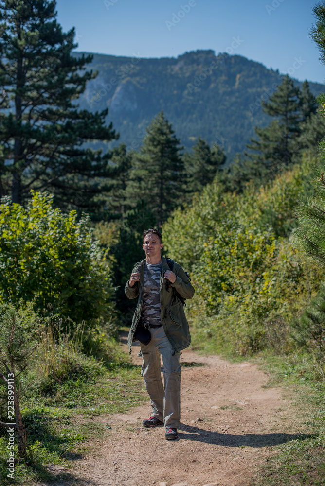 Obraz premium hiker on dirt road out of forest 