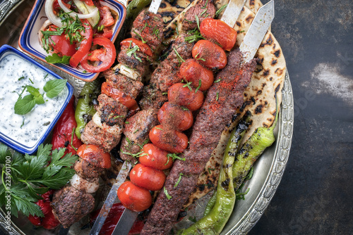 Traditional oriental Adana kebap and shashlik skewer with tomato and flatbread as top view on a plate