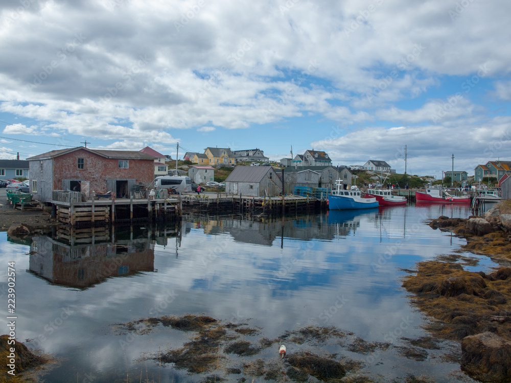 Peggy's Cove Harbour with boats at low tide, summer, clouds in blue sky, peaceful