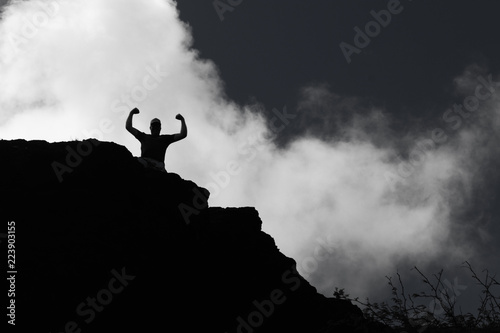 Self empowerment and success with mans sillhouette on top of mountain.