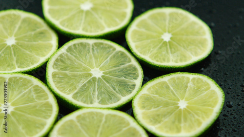 Closeup circle slices of fresh sour green lime on dark background 