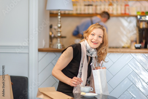 A girl shopping has a rest in a cafe, considering buying and drinking coffee
