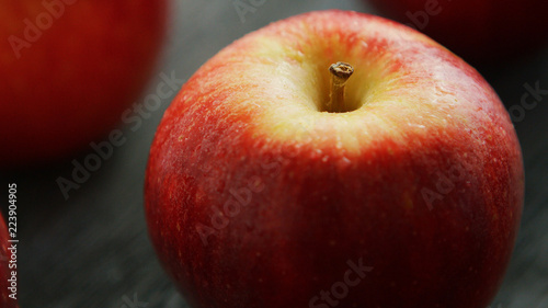Closeup shot of sweet ripe apple with shiny red skins in water drops reflecting daylight