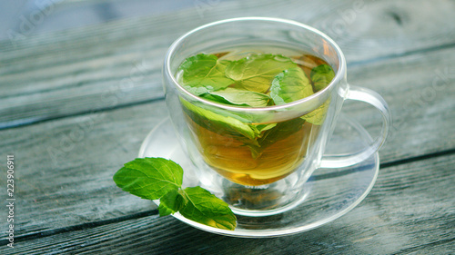 From above view of glass mug of tea with mint on wooden background