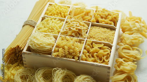 Wooden box filled with plenty of various macaroni and pasta with spaghetti in bunch