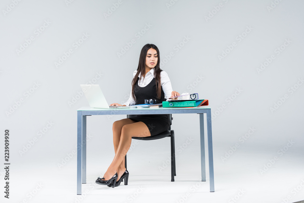 Business woman sitting at working table with paper isolated on gray background Business woman sitting at working table with paper isolated on gray background