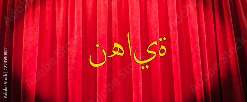 Red a curtain with a graphic inscription in Arabic, with the translation of 