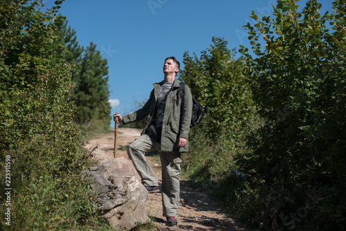 hiker leaning on rock and holding stick in hands