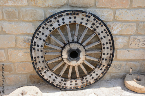 old, ancient wooden wheel with a metal rim, against the background of a stone wall