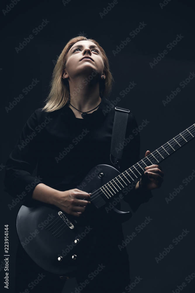 Blonde guitar girl on dark scene, black wall Blonde guitar girl on dark scene, black wall