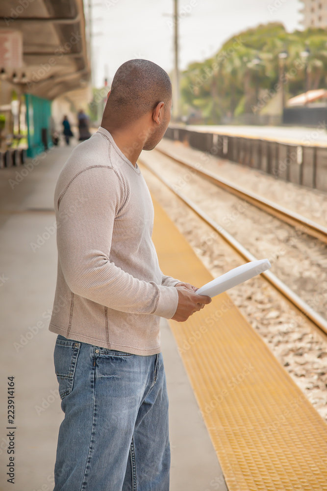 Fototapeta premium The African American black man holding paper looks back to see if a train is coming.