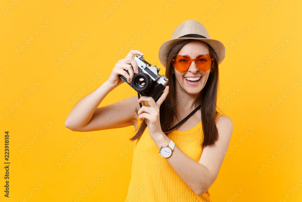 Tourist woman in summer casual clothes, hat take picture on retro vintage photo camera isolated on yellow background. Girl traveling abroad to travel on weekends getaway. Air flight journey concept.