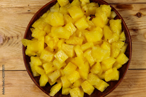 Diced pineapple in a plate on wooden table. Top view