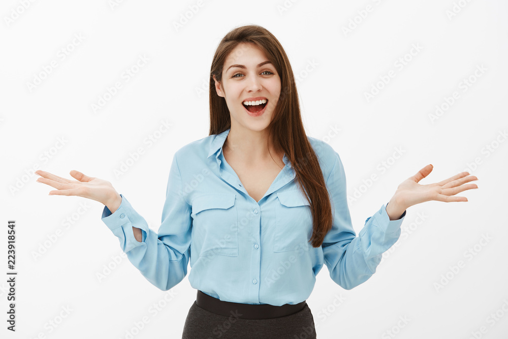 Can you believe it, happy like never before. Portrait of joyful excited european woman in blue formal blouse, spreading palms and smiling broadly, sharing perfect news, standing over gray background