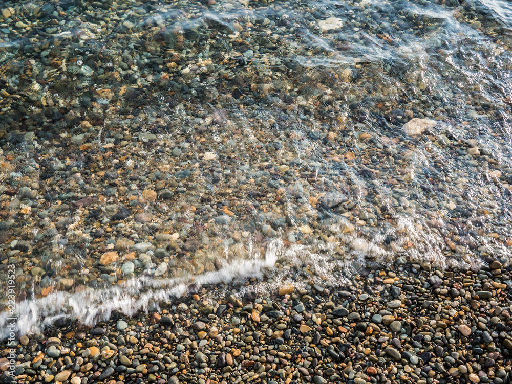Obraz premium pebble beach and clear surf wave. sea coast