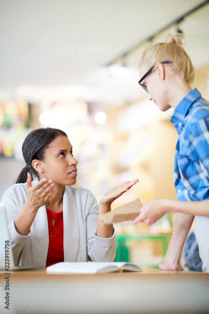 Confident businesswoman in smart casual talking to waitress while ordering lunch in cafe Confident businesswoman in smart casual talking to waitress while ordering lunch in cafe