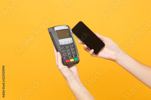 Wallpaper Mural Close up cropped photo female holding in hands wireless modern bank payment terminal to process and acquire credit card payments mobile phone isolated on yellow background. Copy space for advertising. Torontodigital.ca