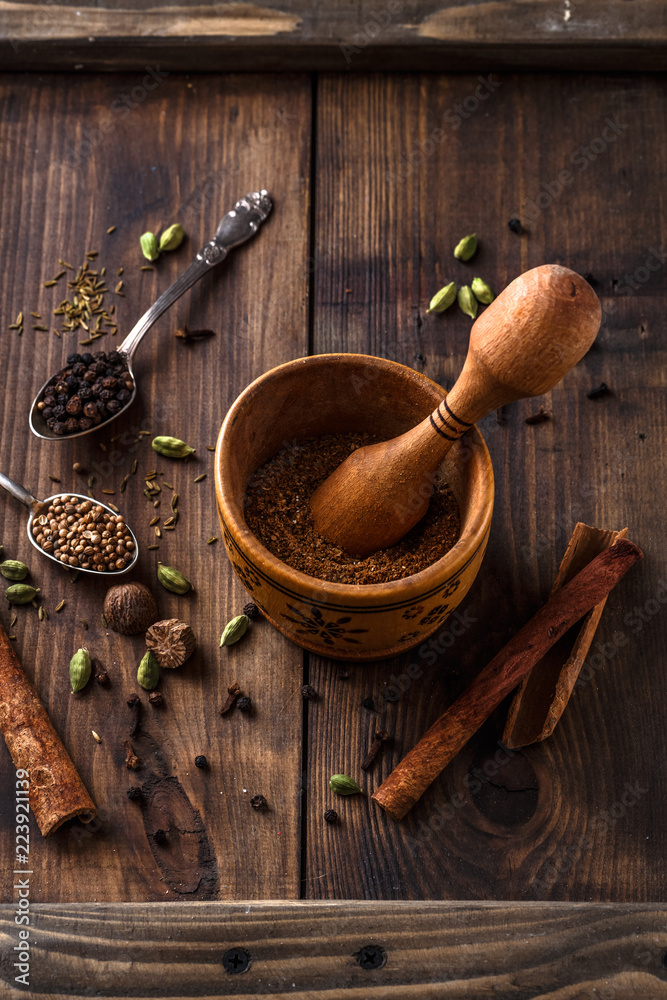 Indian Garam masala powder with ingridients on wooden background Indian Garam masala powder with ingridients on wooden background