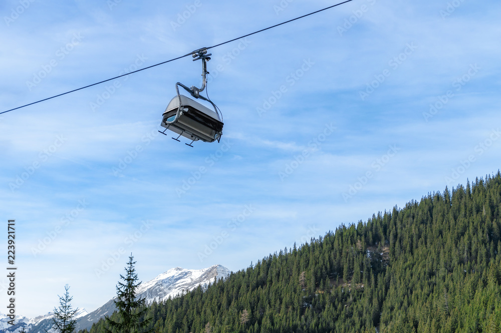 Ski lift against blue sky over wooded Alps Ski lift against blue sky over wooded Alps