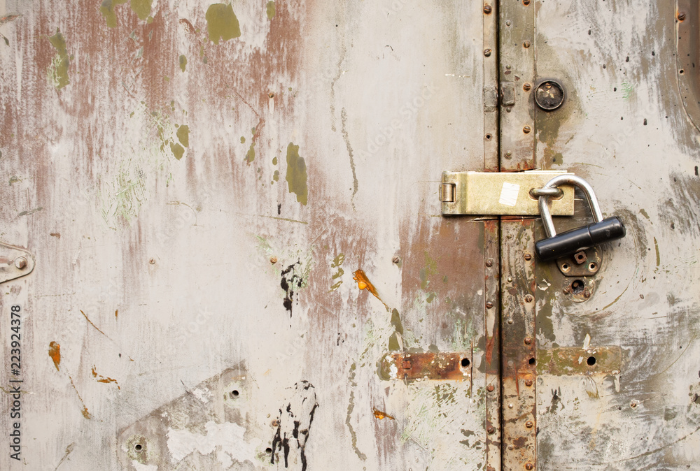 Big black lock hanging on a painted iron ragged door Big black lock hanging on a painted iron ragged door