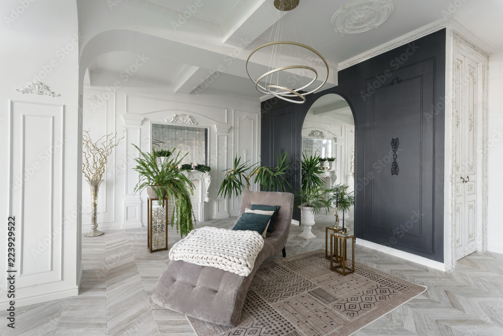 Fototapeta premium Morning in luxurious light interior in hotel. Bright and clean interior design of a luxury living room with parquet wood floors, fireplace, sofa and houseplant. Stucco on walls