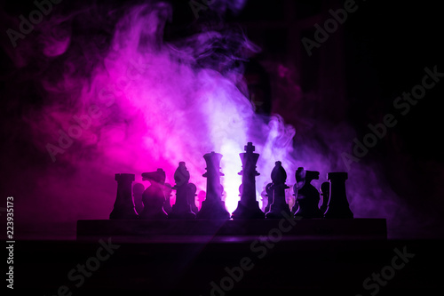 Man playing chess. Scary blurred silhouette of a person at the chessboard with chess figures. Dark toned foggy background.