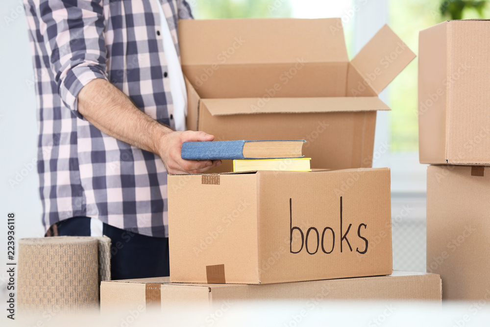 Man putting books into box indoors, closeup. Moving day Man putting books into box indoors, closeup. Moving day