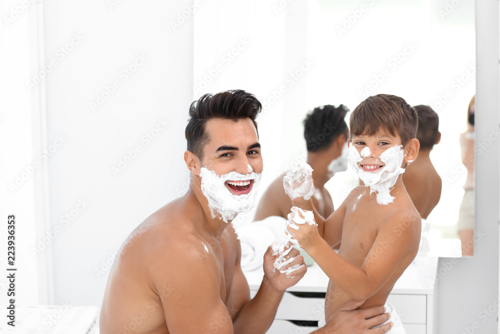 Father and son having fun while applying shaving foam in bathroom