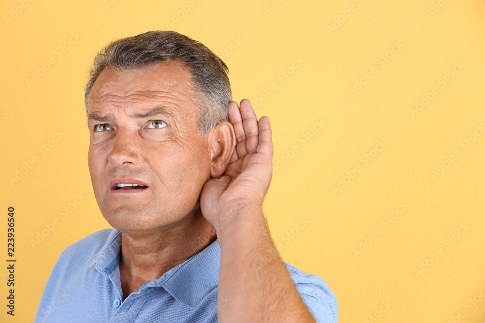 Fototapeta premium Mature man with hearing problem on color background. Space for text