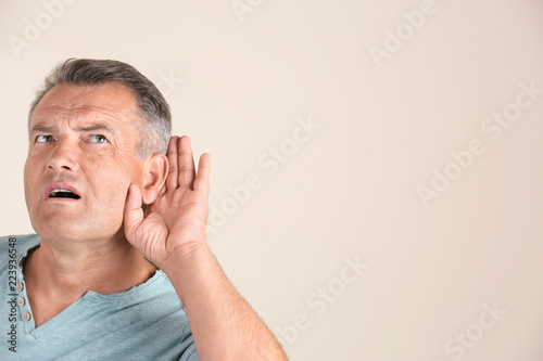 Canvas Print Mature man with hearing problem on light background