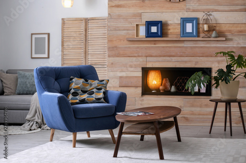 Cozy furnished apartment with niche in wooden wall and armchair. Interior design