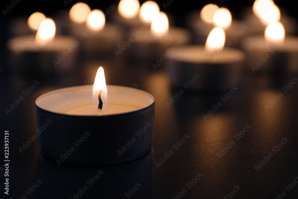 Burning candle on table in darkness, closeup with space for text. Funeral symbol Burning candle on table in darkness, closeup with space for text. Funeral symbol